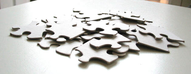 White puzzle pieces piled on white table