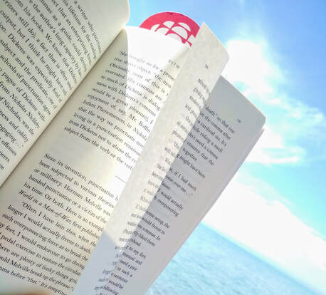 Open book page against background of blue sky, clouds, and a lake